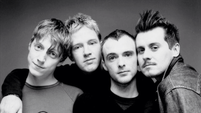 A black-and-white portrait of the four members of Travis standing shoulder to shoulder.