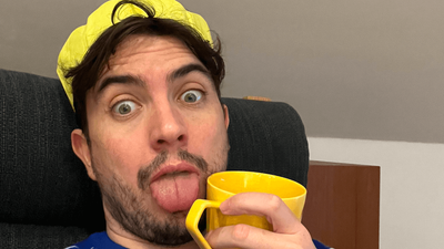 Jack wearing a yellow paper crown and holding a yellow mug, sticking his tongue out at the camera.