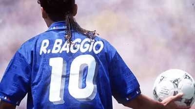 Roberto Baggio seen from behind in Italy’s blue number 10 shirt at the 1994 World Cup, holding a football.