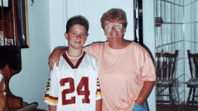 Aunty Betty smiling with her arm around Jack, who is wearing a number 24 Washington Redskins jersey.